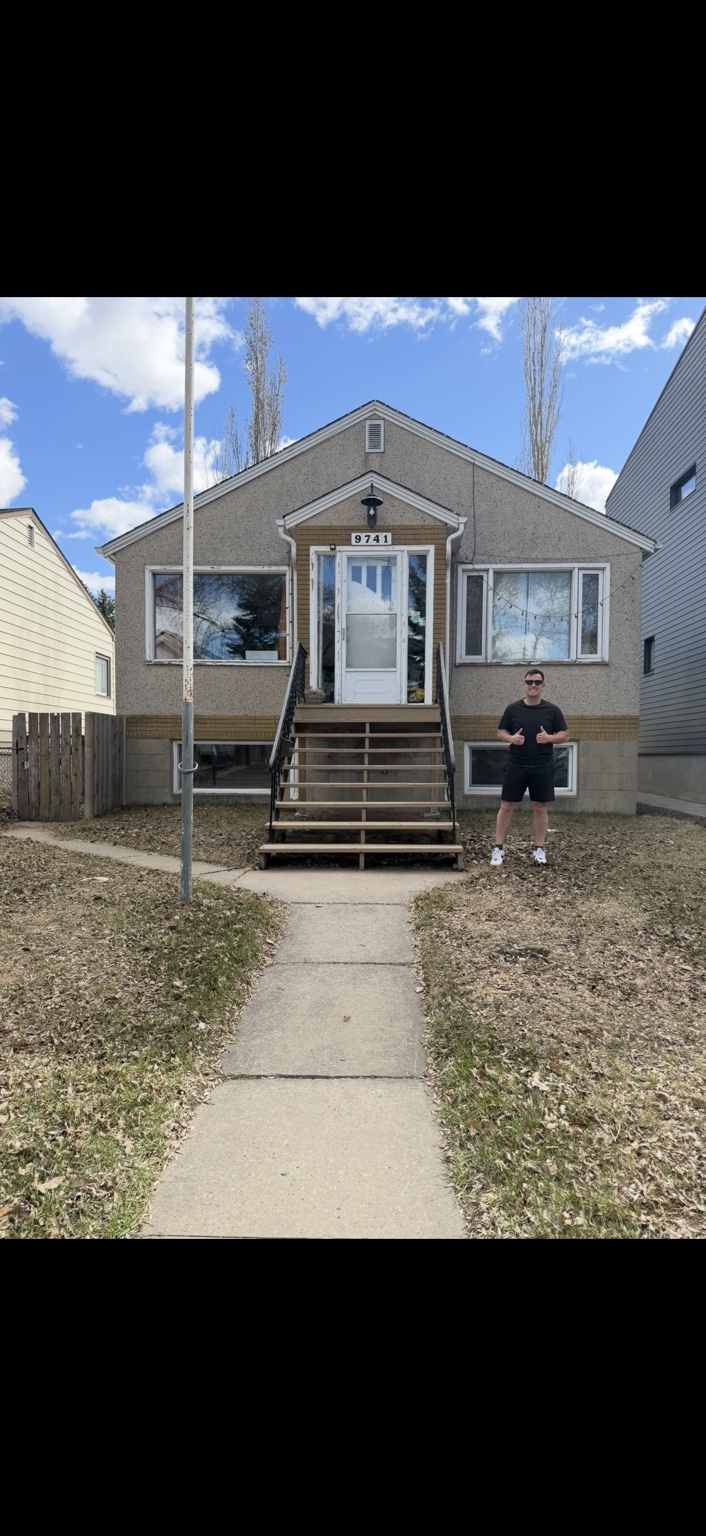 Brandon standing outside a grey bungalow with front steps