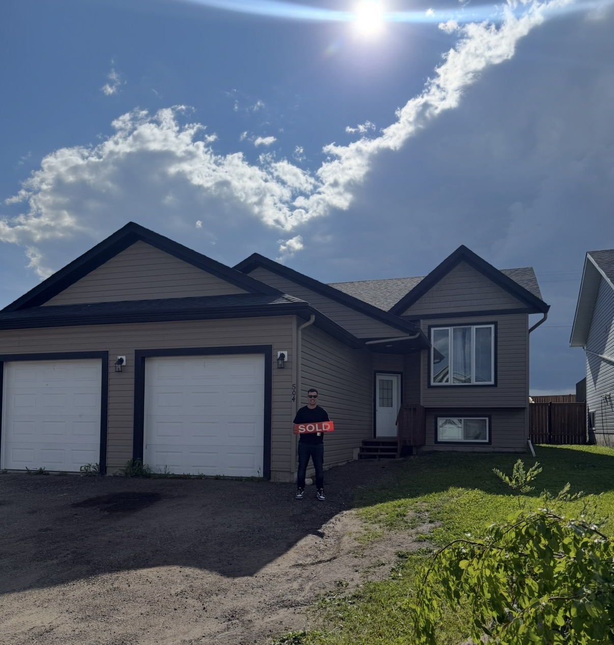 Two-storey home with attached garages and a sold sign
