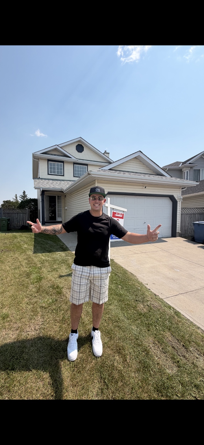 Brandon standing outside a two-storey home with a garage