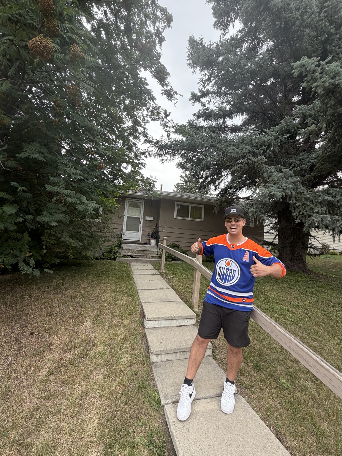 Brandon standing outside a home shaded by mature trees