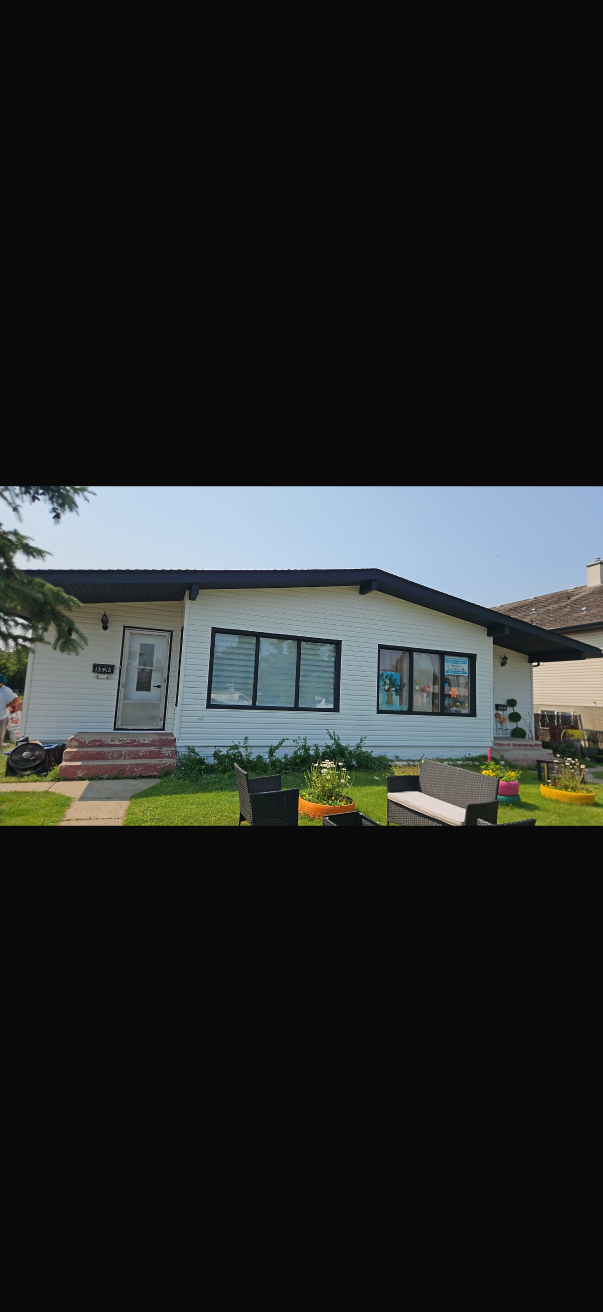 White single-storey property with dark trim and a front lawn