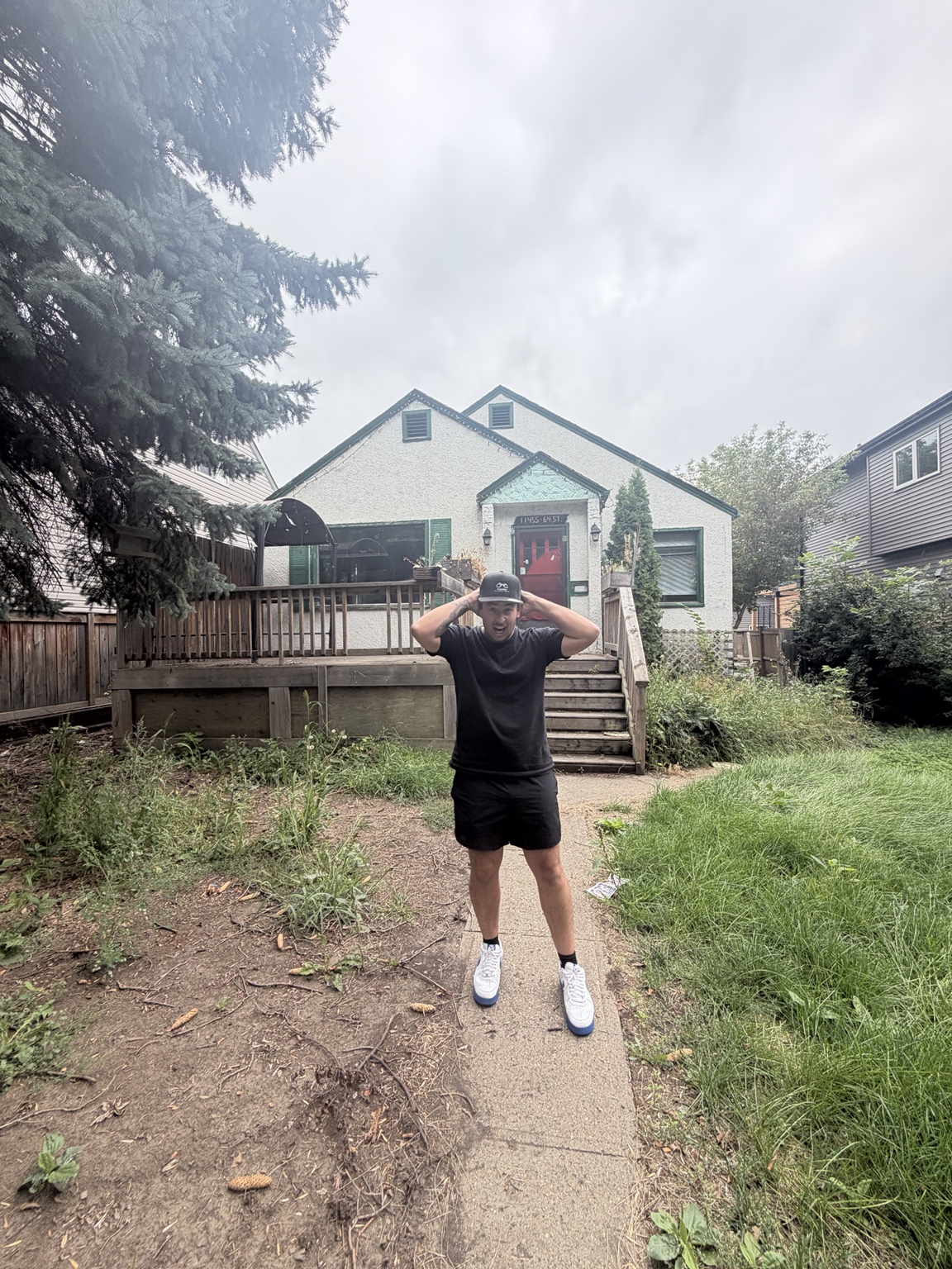 Brandon standing outside a light-coloured house with a front deck