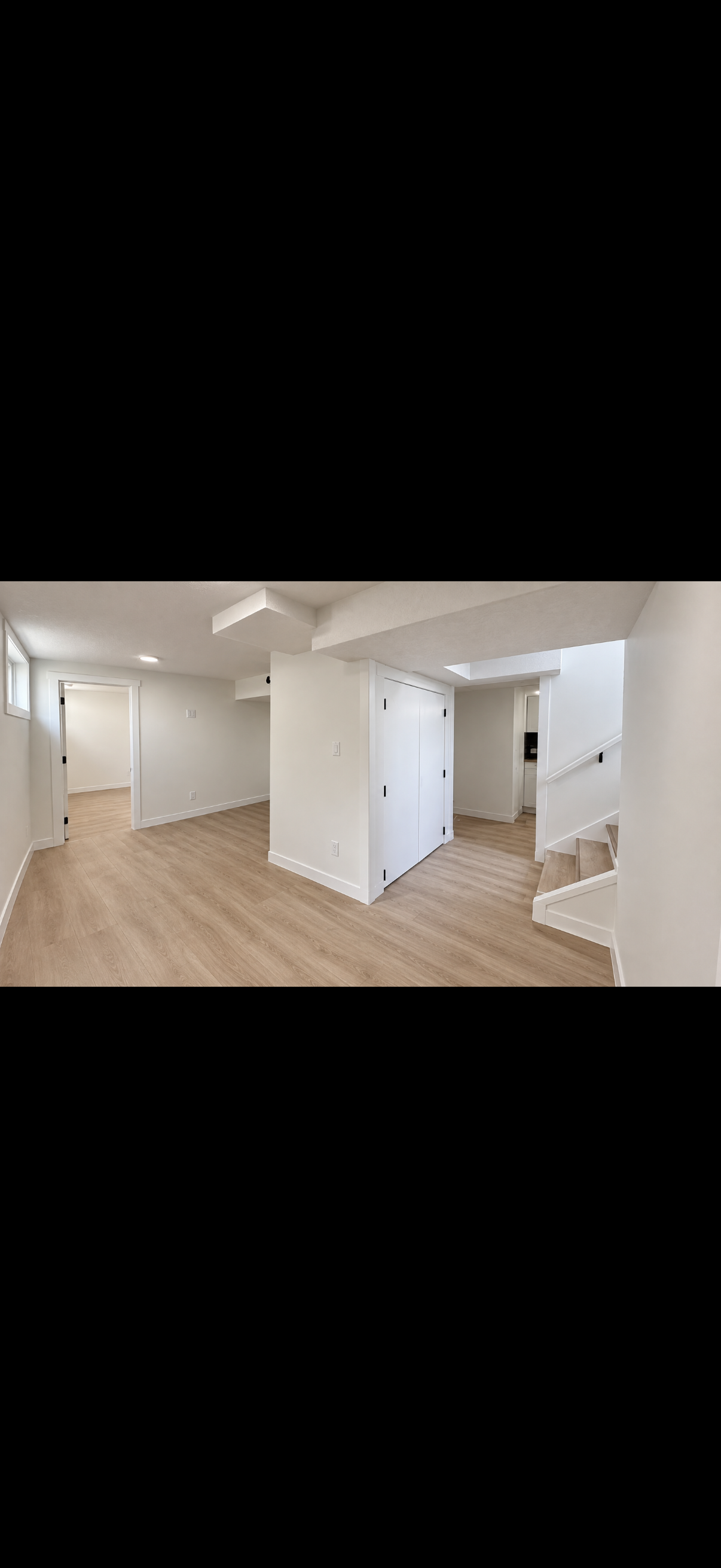 Finished basement interior with light flooring and white walls
